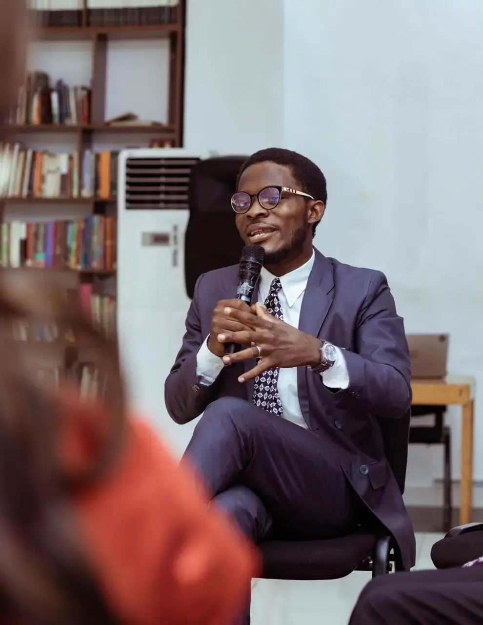 Simon Akinlabi speaking into a microphone before an audience