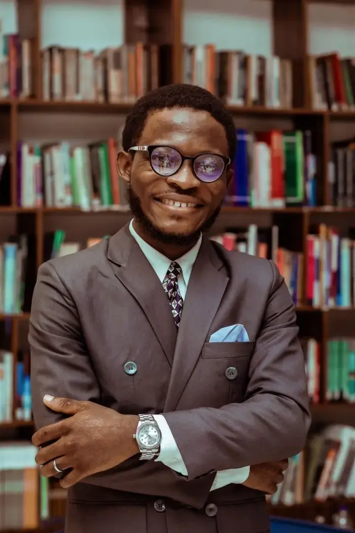 Simon Akinlabi standing before library bookshelves